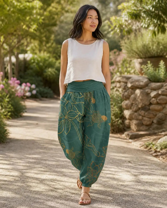 Model wearing green Lotus Koi Renewal Harem Pants in a sunlit garden